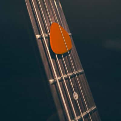 Médiator orange sur manche de guitare