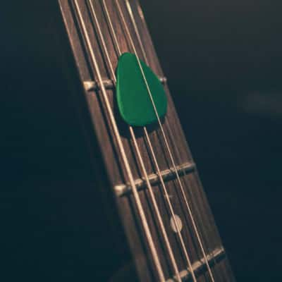 Médiator vert sur manche de guitare